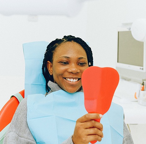 Woman in dentist’s chair looking in hand mirror